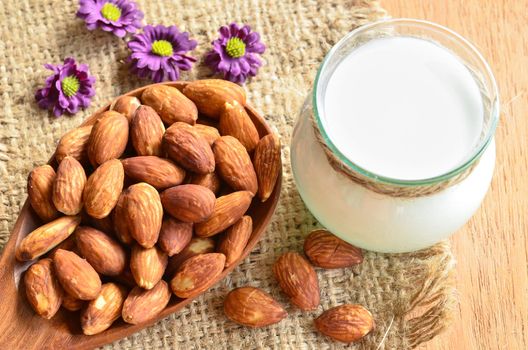 Almond with milk almond and violet flower on wooden background.