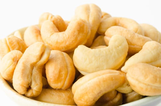 Close up cashew nuts with salt in wooden cup on white background.