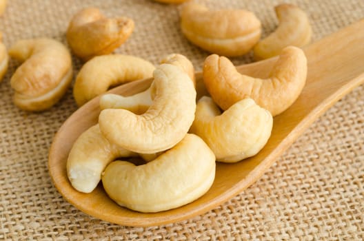 Cashews close-up in wooden spoon on sackcloth