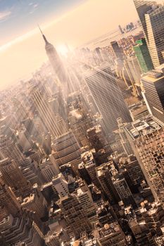 New York City. Manhattan downtown skyline with illuminated Empire State Building and skyscrapers at sunset. Vertical composition. Warm evening colors. 