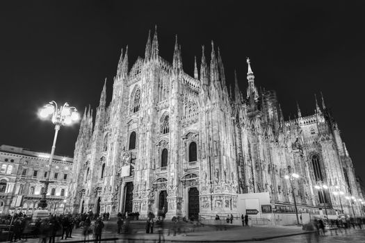 Milan Cathedral, Duomo di Milano. Famous gothic cathedral church of Milan, Italy, Europe. Black and white image shot at dusk from square full of people.