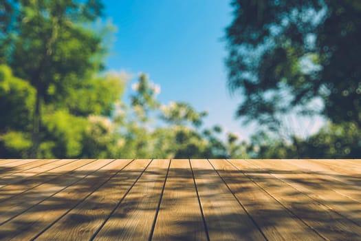 Beautiful sunlight in the autumn forest with wood planks floor, nature background, bokeh background