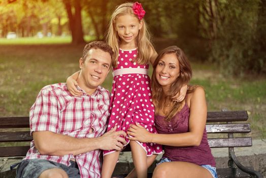 Portrait of a beautiful smiling family enjoying in the park. Looking at camera.