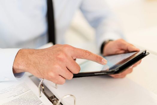 Close-up of a businessman hands touching his digital tablet.