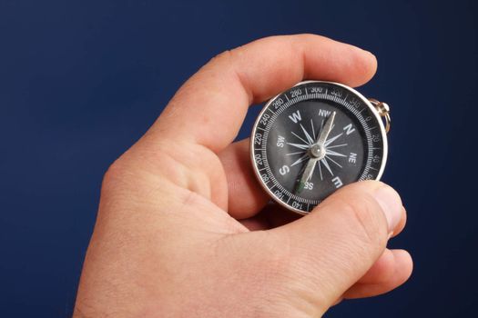 male hand holding compass over blue