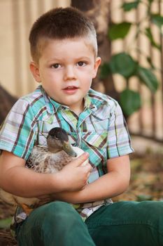 Single smiling child holding a duck outdoors