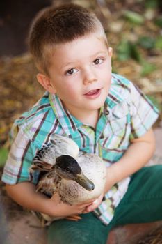 Adorable child playing with little duck outdoors