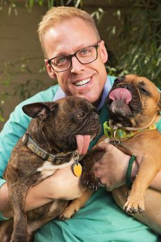 Smiling man with eyeglasses holding two dogs