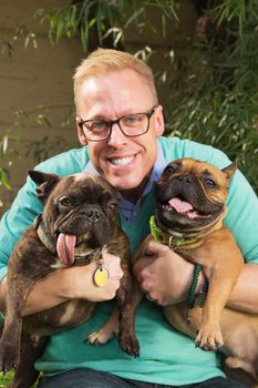 Blond man smiling with pair of bulldogs