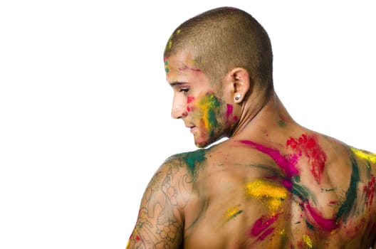 Handsome young man seen from the back with skin all painted with Holi colors, isolated on white background