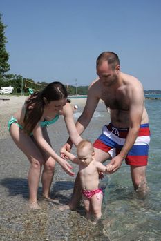 Mother and father with their baby girl enjoying on the beach