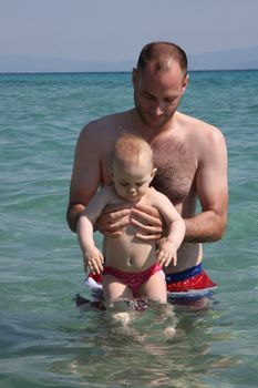 Father halps his baby daughter to to feel good in the sea water