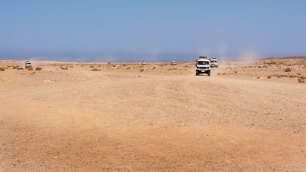 Egypt, Black Desert. Moving off-road vehicle with a panoramic view on the stone desert . Tracks on the sand from the automotive rubber.