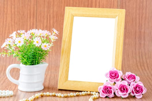 Blank wooden photo frame and pink rose on wooden background. Save clipping path.