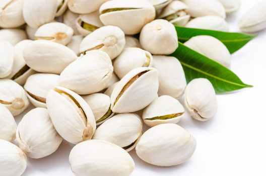 pistachios closeup and green leaf on white background