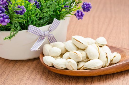 Pistachios. Selective focus and flower on wooden background.