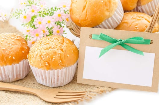 Bread bun and blank paper tag with flower on white background.