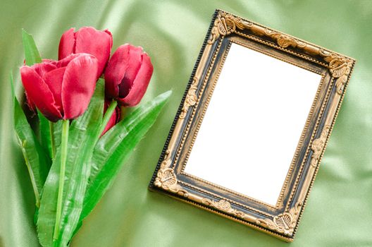 Blank Picture frames and red tulips flowers on green green silk fabric background. save clipping path.