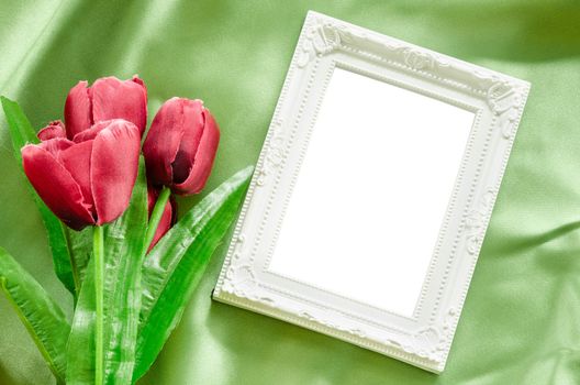 Blank Picture frames and red tulips flowers on green green silk fabric background. save clipping path.