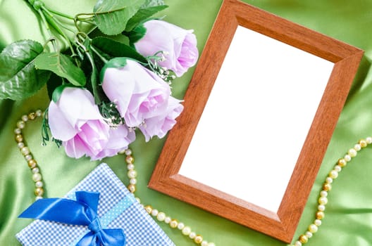 Blank wooden photo frame and tulip on green fabric. Save clipping path.