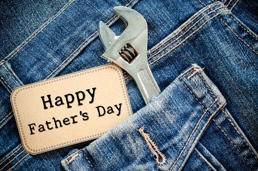 Closeup father's day card love father or daddy or papa in pocket jeans -- Happy Labor Day on blackboard with tool steel iron wrench silver chrome. holiday for worker.