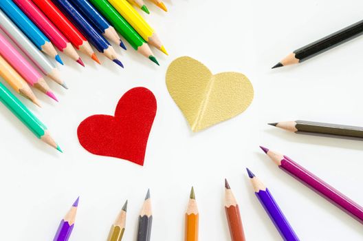 Color pencils and paper heart shape on white background.