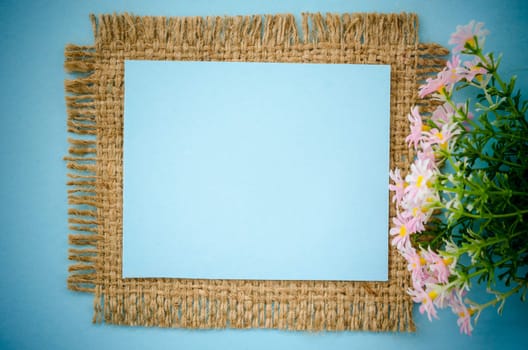 Blue paper blank card on sack with pink flower for your text.