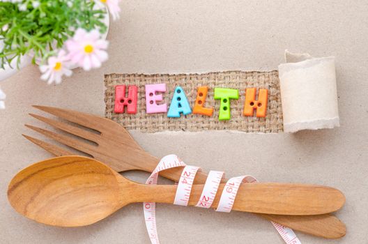 Health word and wooden spoon with Measure tape on brown paper background.