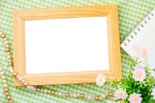 Blank vintage wooden photo frame and open diary with pink flower on fabric background. Save clipping path.