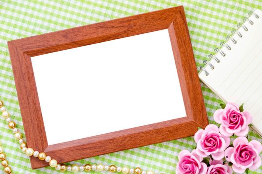 Blank vintage wooden photo frame and open diary with pink rose on fabric background. Save clipping path.