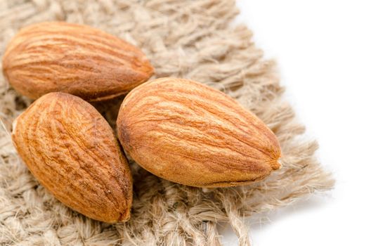 Close up raw almonds on sack background.