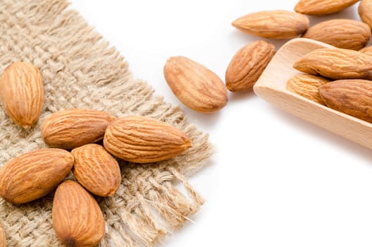 Close up raw almonds in wooden spoon on white background.