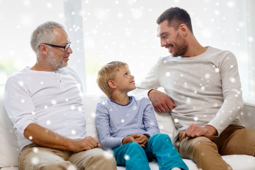 family, happiness, generation and people concept - smiling father, son and grandfather sitting on couch at home