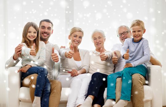 family, happiness, generation and people concept - happy family sitting on couch and showing thumbs up gesture at home
