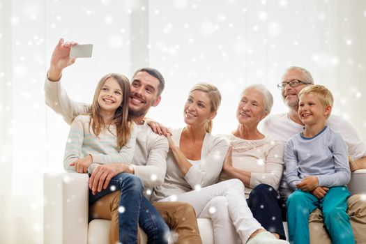 family, technology, generation and people concept - happy family sitting on couch and making selfie with smartphone at home