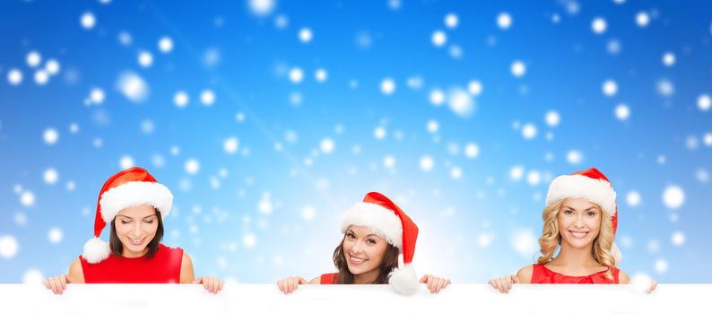 christmas, x-mas, people, advertisement and sale concept - happy women in santa helper hat with blank white board over blue snowy background