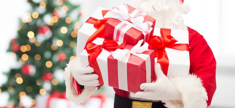 christmas, holidays and people concept - close up of santa claus with gift box over living room with tree