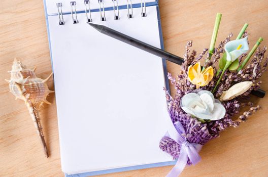Blank open diary and black pencil with flower on wooden background. Free space for your text.