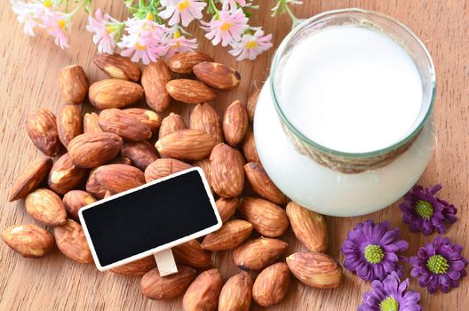 Almond and almond milk with blank black wooden tag for your text on sack background.