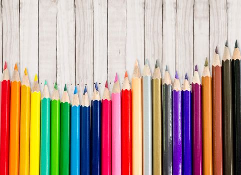 line of colored pencils on wooden background, save clipping path.