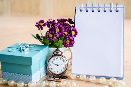Open diary, pocket watch, gift box and flower on wooden backgroudn.