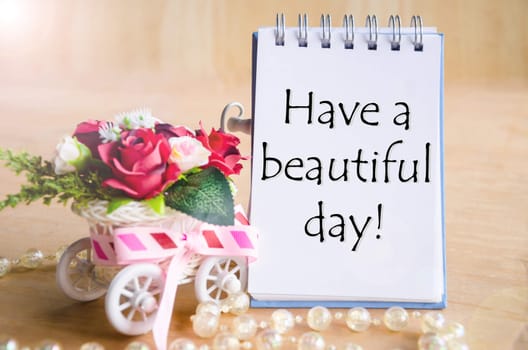 Have a nice day on open diary and and red rose basket on wooden background.