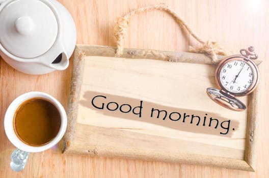 Cup of coffee with wooden board and pocket clock on vintage wooden background