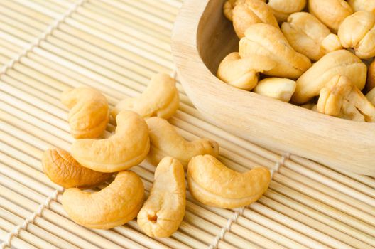 Roasted cashews on natural wooden mat background.