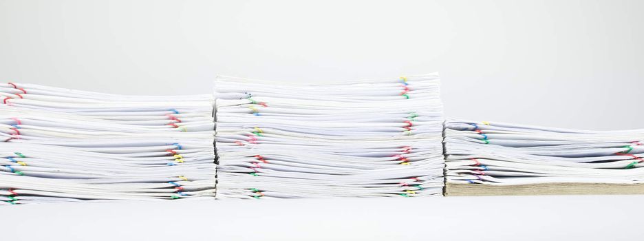 Colorful paper clip with pile of report and brown envelope on white table.