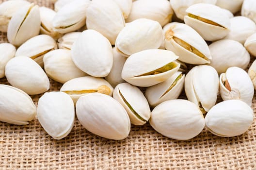 Roasted pistachios on sack background.