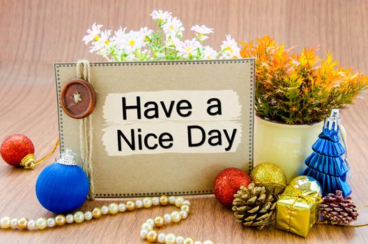 Have a nice day on brown tag with christmas decoration on wooden background.