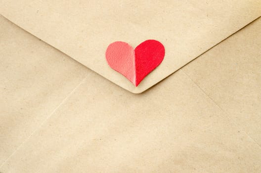 Love letter. Close up Red heart paper on brown envelope.