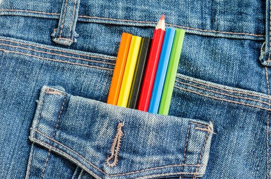 Artist painting concept. Many color pencil in blue jeans pocket background.