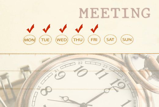 Close up meeting date on diary with pocket watch.